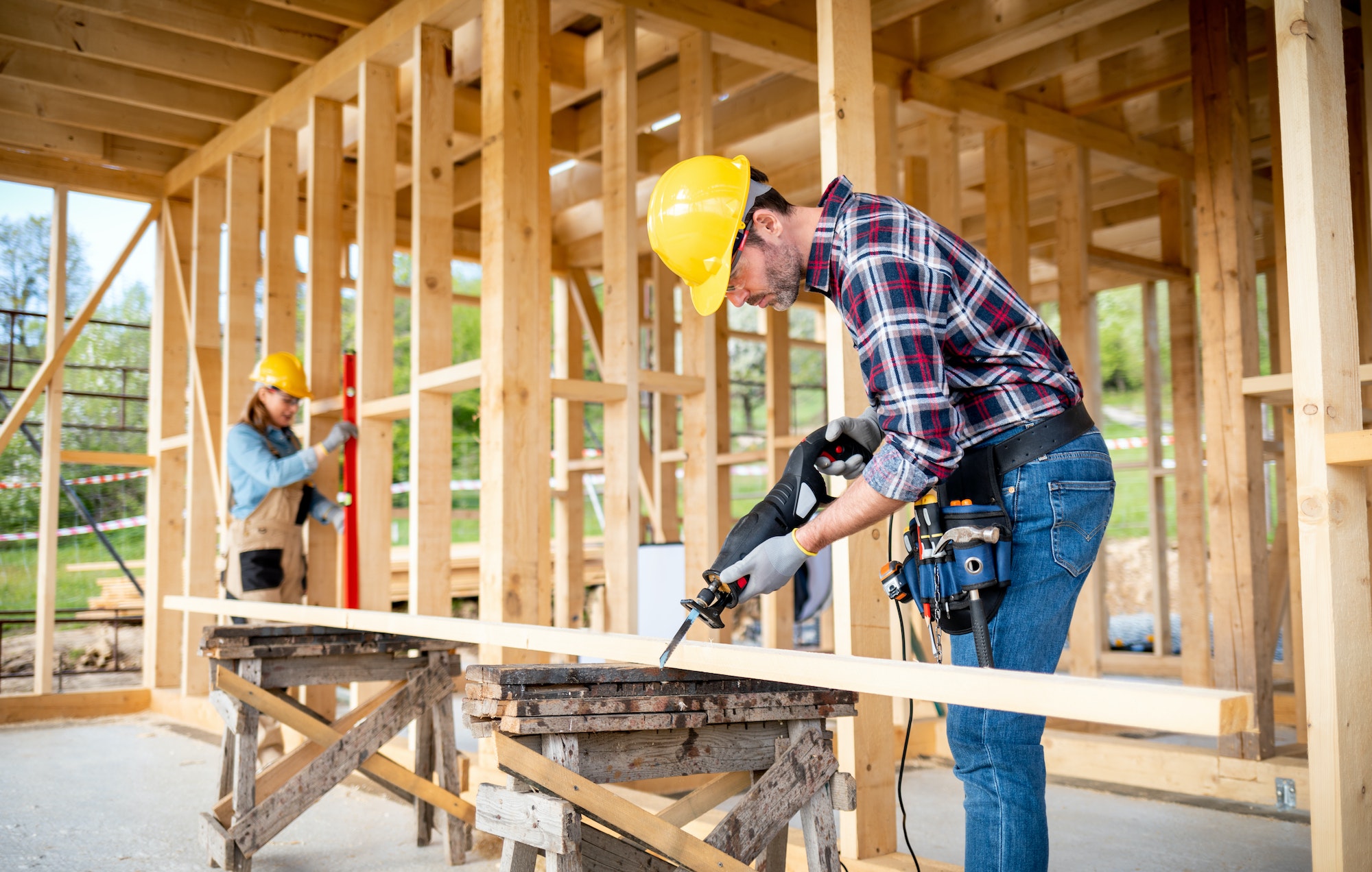 Team of workers doing woodwork at construction site of wood frame house